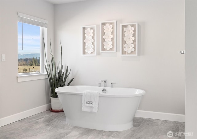 bathroom featuring a soaking tub and baseboards