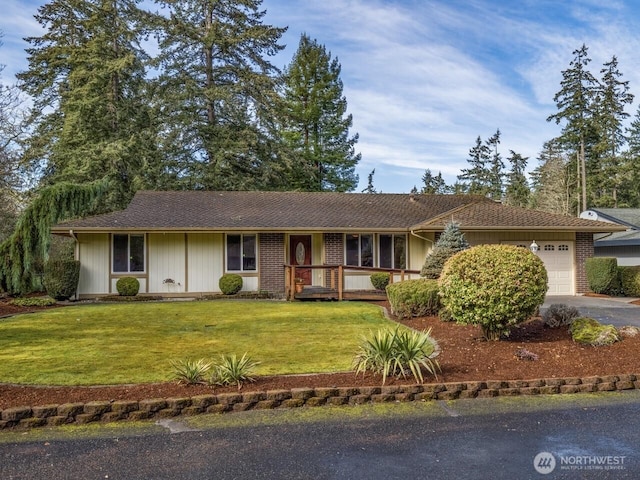 ranch-style home with a garage, driveway, brick siding, and a front yard