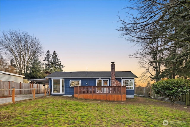 rear view of property with a lawn, a deck, an attached carport, a fenced backyard, and driveway