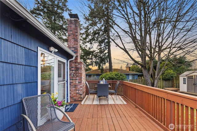 deck with an outbuilding, outdoor dining area, and a storage shed