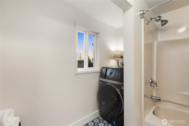 clothes washing area featuring washer / dryer, laundry area, and baseboards