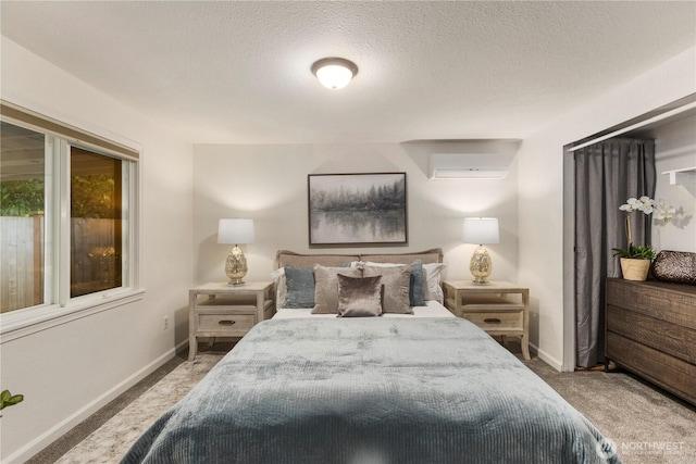 carpeted bedroom featuring a wall mounted air conditioner, a textured ceiling, and baseboards