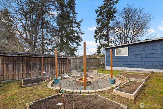 view of yard featuring an outdoor fire pit, a garden, fence, and a patio