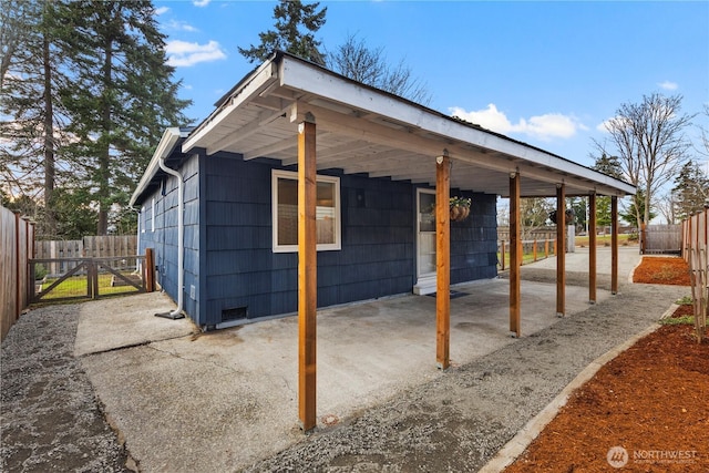 view of outdoor structure featuring a gate, fence, and an attached carport