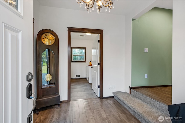 foyer featuring visible vents, baseboards, a chandelier, and wood finished floors