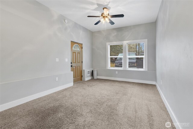 carpeted spare room featuring a ceiling fan and baseboards