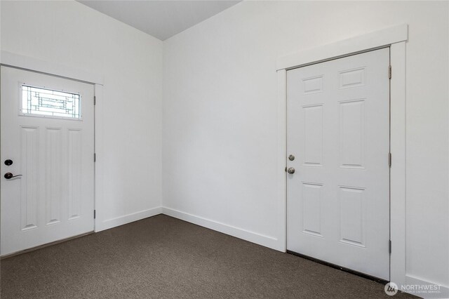 entryway featuring baseboards and dark carpet