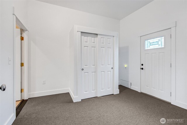 foyer entrance with dark colored carpet and baseboards