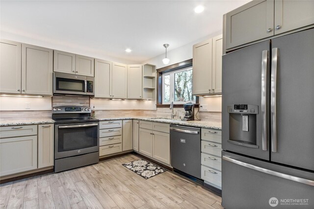 kitchen featuring open shelves, stainless steel appliances, hanging light fixtures, and gray cabinetry