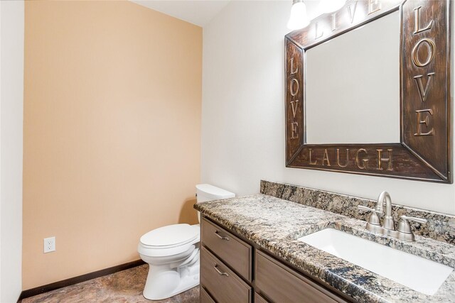 bathroom with baseboards, vanity, and toilet