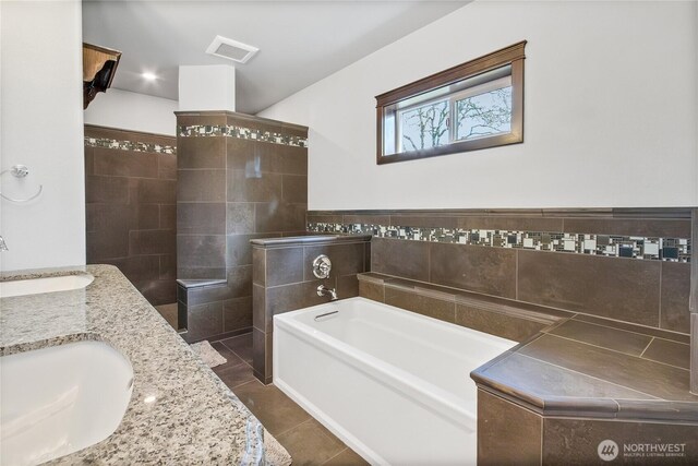 bathroom with a garden tub, a sink, visible vents, tile patterned floors, and double vanity