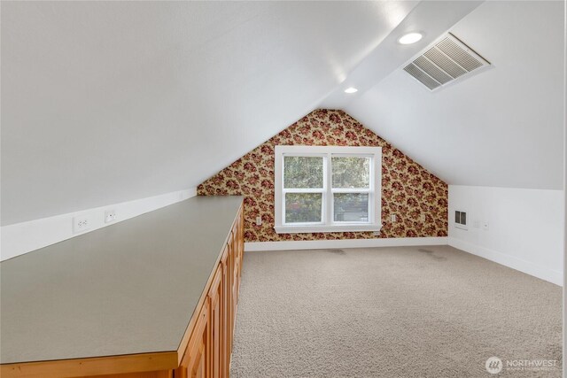 additional living space with lofted ceiling, baseboards, visible vents, and light colored carpet