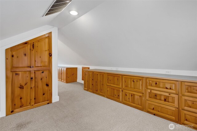 additional living space with lofted ceiling, visible vents, and light carpet