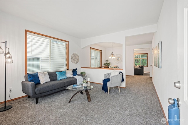 living room with carpet floors, arched walkways, baseboards, and an inviting chandelier