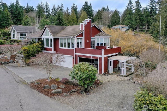 view of front of home featuring driveway, an attached garage, and a chimney