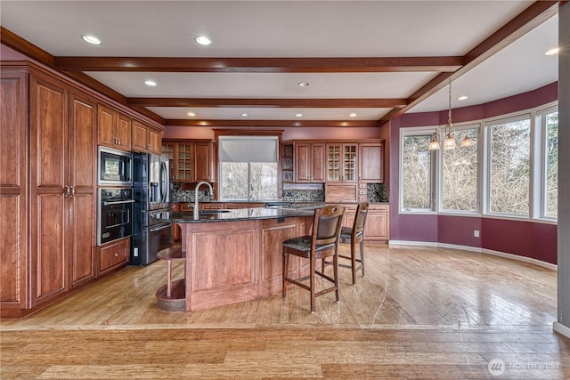 kitchen with dark stone counters, appliances with stainless steel finishes, a breakfast bar area, and glass insert cabinets