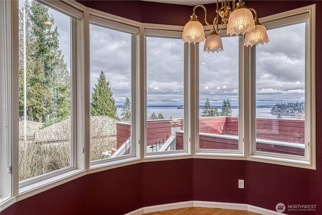 unfurnished sunroom featuring a chandelier and a water view