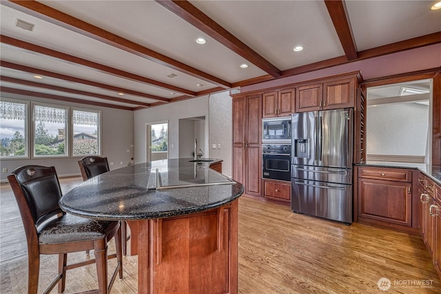 kitchen featuring a center island, stainless steel refrigerator with ice dispenser, a sink, built in microwave, and black oven