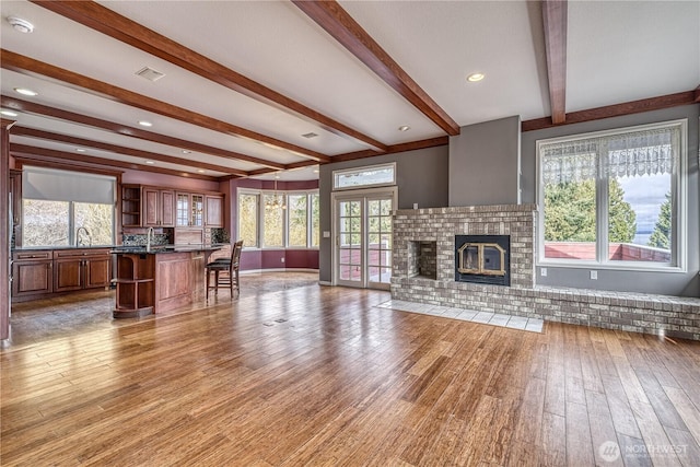 unfurnished living room featuring light wood-type flooring, a wealth of natural light, a fireplace, and a sink