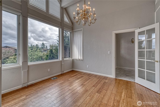 spare room with baseboards, visible vents, wood finished floors, and a textured wall