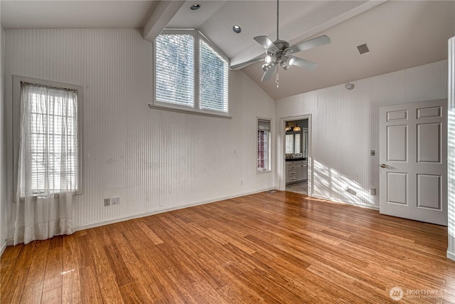 spare room featuring light wood-type flooring, plenty of natural light, a ceiling fan, and beamed ceiling