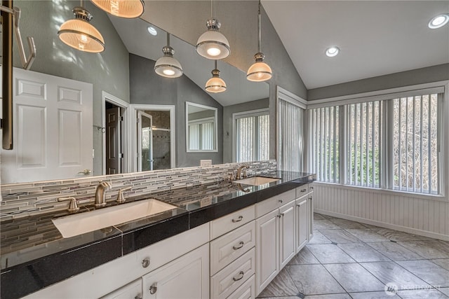 bathroom featuring vaulted ceiling, double vanity, and a sink