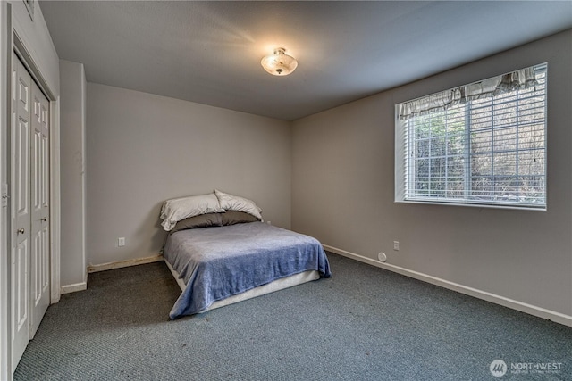 bedroom with baseboards, dark carpet, and a closet