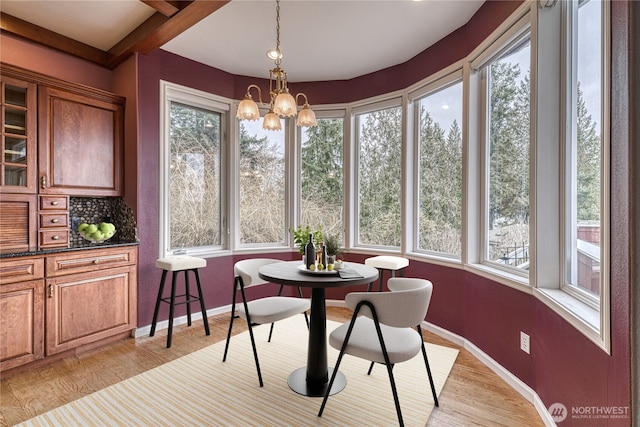 sunroom with a notable chandelier and beamed ceiling