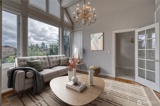 living room with lofted ceiling with beams, a textured wall, a chandelier, wood finished floors, and baseboards