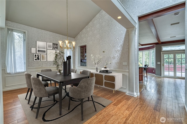 dining space with vaulted ceiling with beams, a wainscoted wall, light wood-style flooring, and wallpapered walls