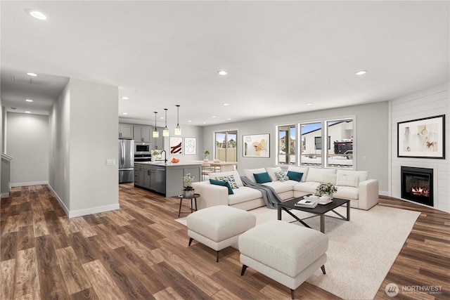 living area featuring dark wood-style floors, a fireplace, baseboards, and recessed lighting