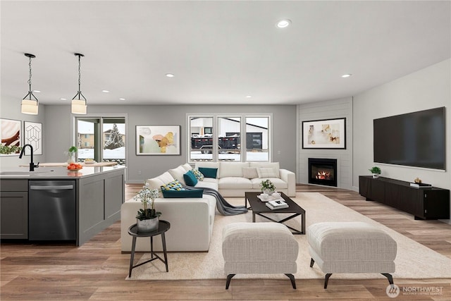 living room with recessed lighting, a fireplace, and light wood-style flooring