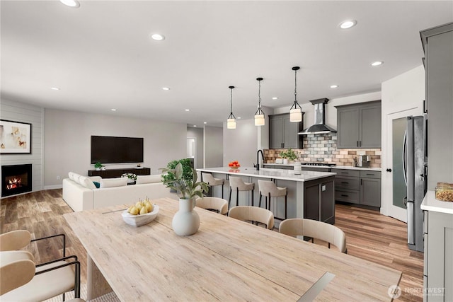 dining room with light wood-style flooring, a fireplace, baseboards, and recessed lighting