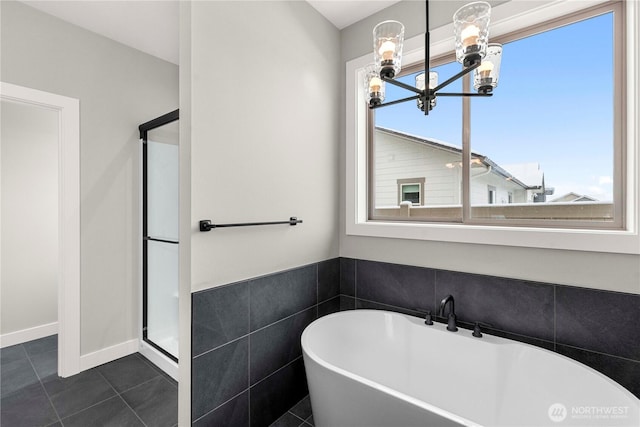 bathroom featuring a freestanding tub, a notable chandelier, tile walls, tile patterned floors, and a stall shower