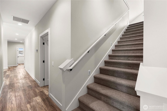 stairway with baseboards, wood finished floors, visible vents, and recessed lighting