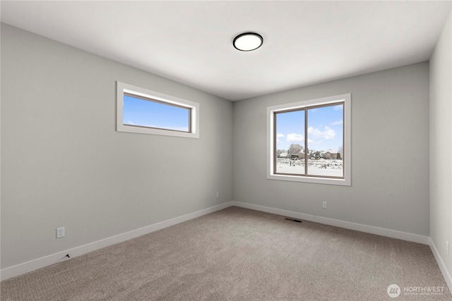 carpeted empty room with a healthy amount of sunlight, baseboards, and visible vents