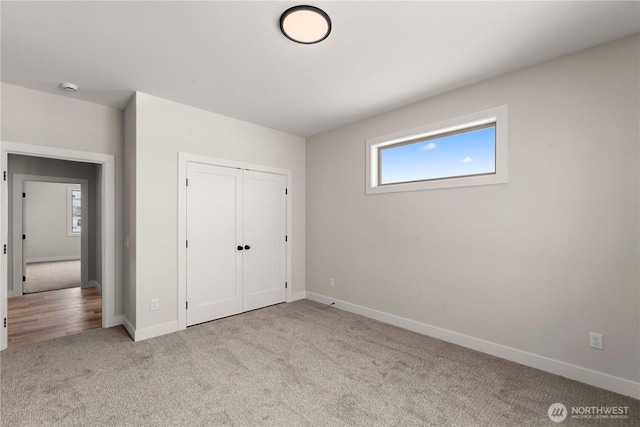 unfurnished bedroom featuring light carpet, a closet, and baseboards