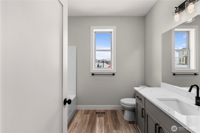 bathroom featuring visible vents, toilet, vanity, wood finished floors, and baseboards