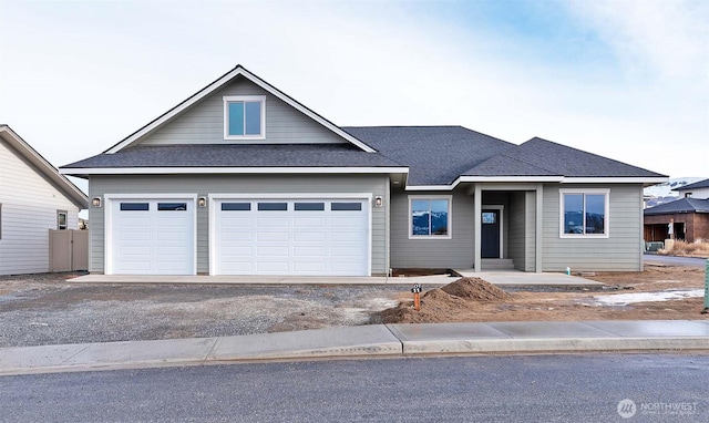 view of front of property featuring a garage, aphalt driveway, and roof with shingles