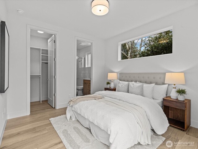 bedroom with connected bathroom, baseboards, a closet, light wood-type flooring, and a walk in closet