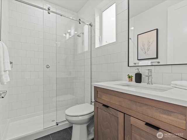 full bathroom featuring tile walls, toilet, a stall shower, vanity, and tile patterned flooring