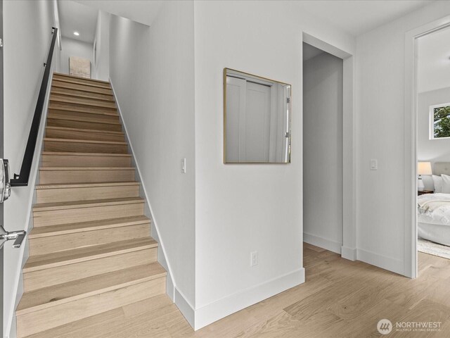 staircase featuring baseboards and wood finished floors