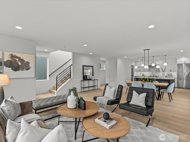 living area featuring light wood-style floors, recessed lighting, and stairs