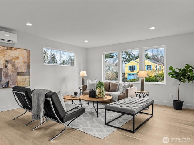 living area with an AC wall unit, recessed lighting, light wood-style flooring, and baseboards