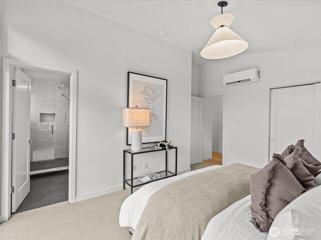 carpeted bedroom with a closet, a wall mounted air conditioner, connected bathroom, and baseboards