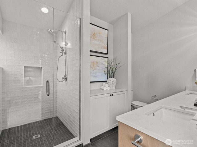 bathroom with double vanity, toilet, a sink, a shower stall, and tile patterned floors