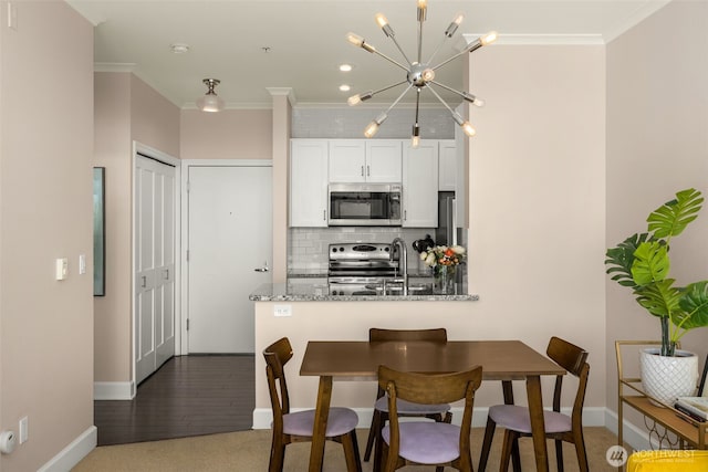 kitchen featuring tasteful backsplash, white cabinets, light stone countertops, stainless steel appliances, and crown molding