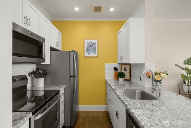 kitchen featuring appliances with stainless steel finishes, white cabinetry, a sink, and light stone counters