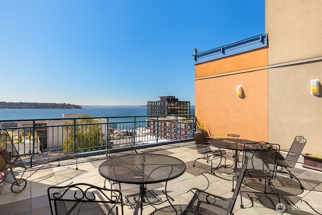 view of patio featuring a water view, a balcony, and outdoor dining area
