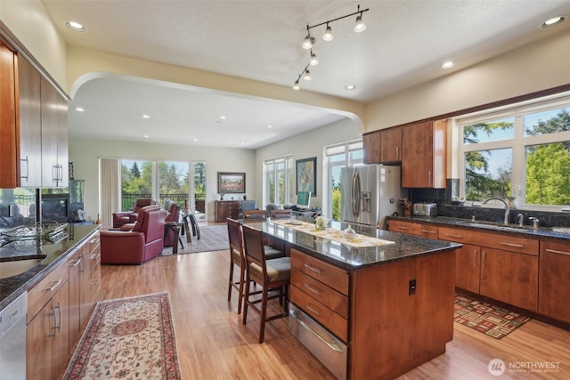 113 Northridge Dr, Ridgefield, WA 98642 - kitchen with arched walkways, a sink, stainless steel fridge with ice dispenser, light wood finished floors, and open floor plan